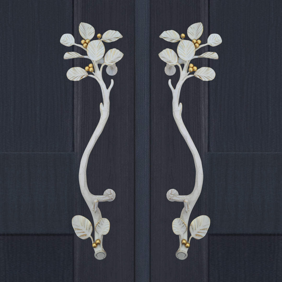 A pair of white and gold luxurious pull handles inspired by nature's leaves mounted on a closed wooden blue door