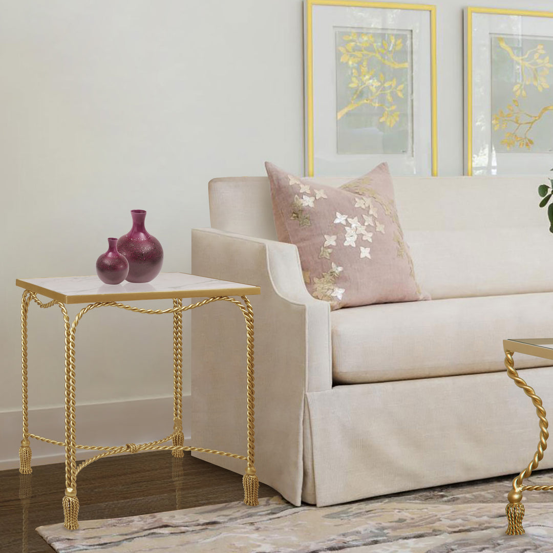 Twisted metal rope-themed side table in golden color and marble top stands at the end of a pink sofa