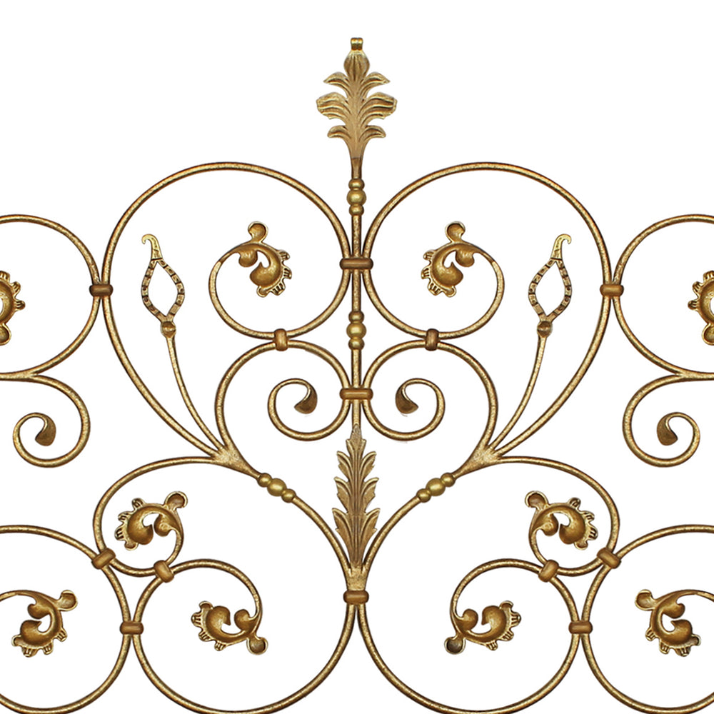 Close up of a classic metal headboard made up of scrolls and leaves, painted in an antique golden finish