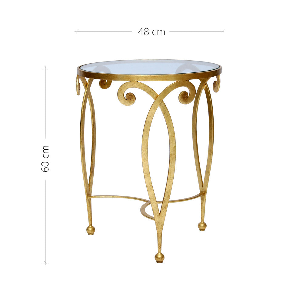 An exquisite golden end table made of metal scrolls topped with a clear round glass