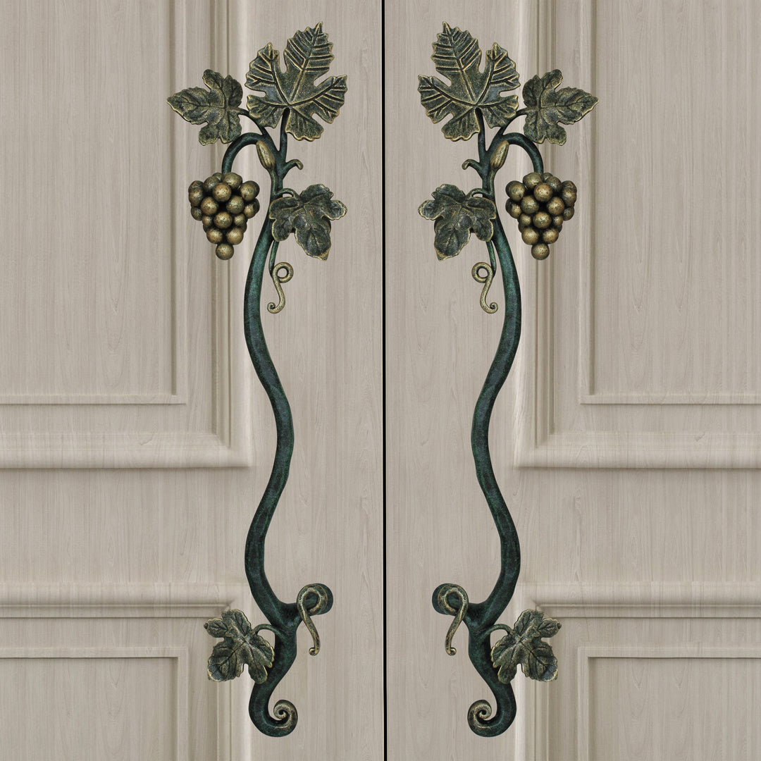 A pair of dark green and gold decorative pull handles inspired by grape vines mounted on closed wooden beige door