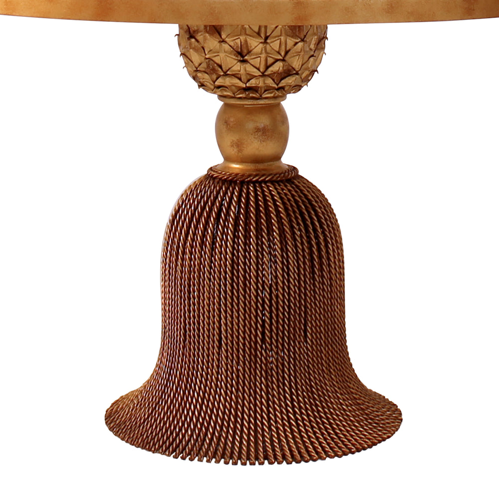 Close up of a round wrought iron foyer table with tassel shaped base; painted in a golden finish