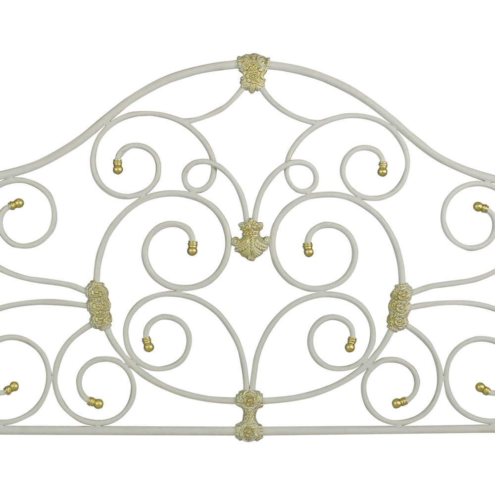 Close up of a metal headboard for a single bed with scrolls and classical motifs, painted in white and gold