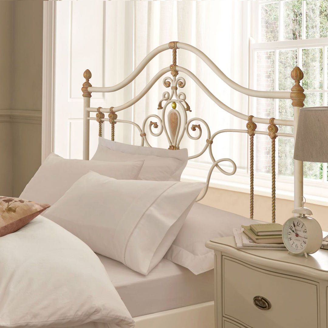 Ornate double bed with floral details and curved wrought iron frame in a light-toned bedroom
