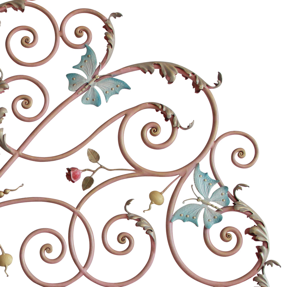 Close up of a handmade metal girly headboard with pink scrolls, blue butterflies and red roses