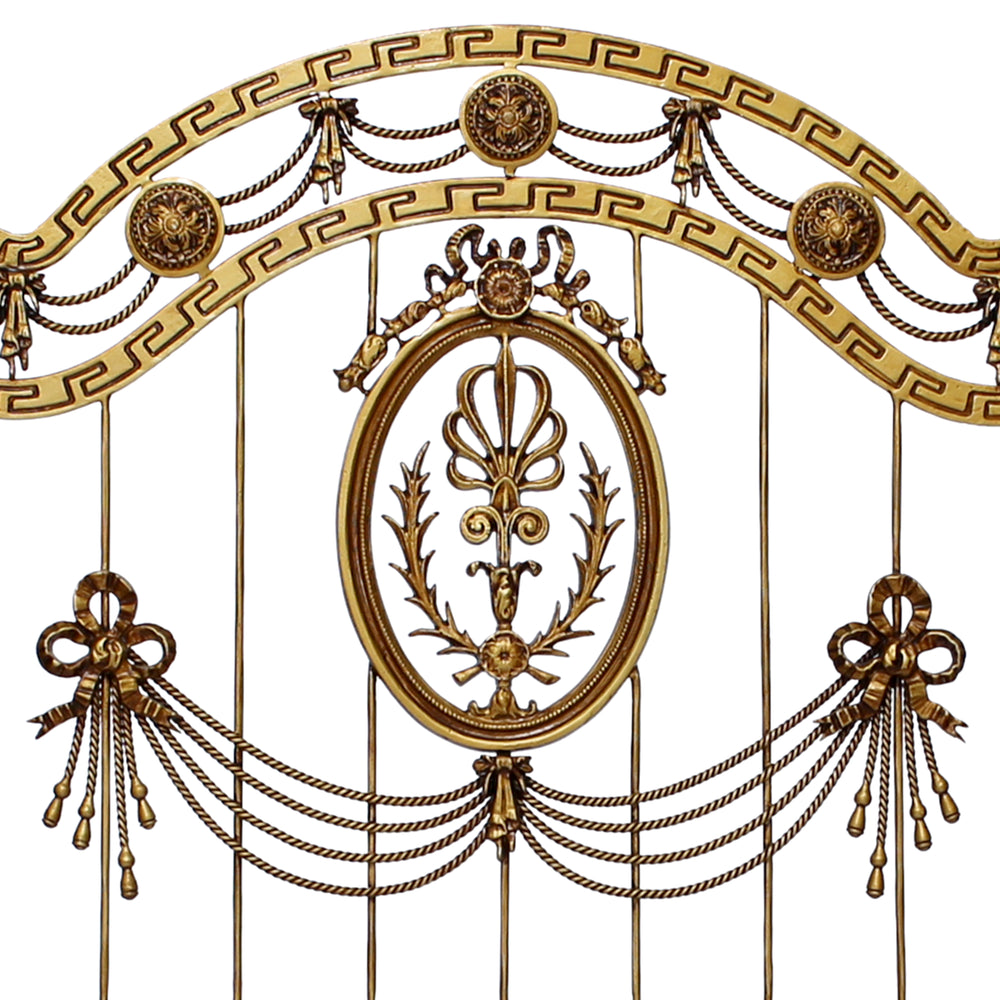 Close up of a wrought iron headboard made up of classical elements and a versace pattern, painted in an antique gold color