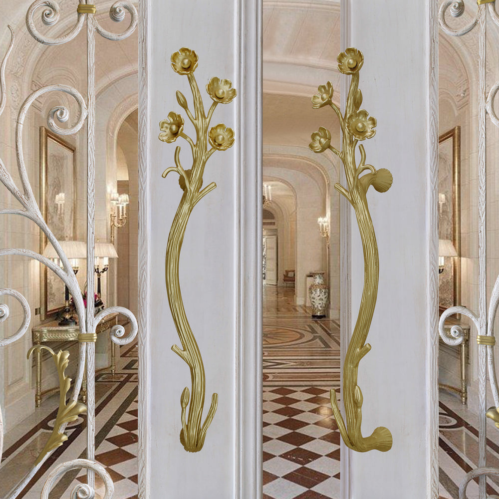 A pair of luxury steel handles with nature inspired branches and flowers mounted on a door