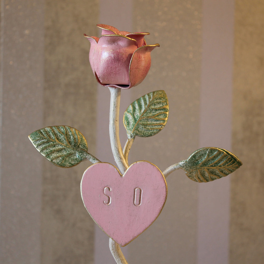 Close up of a decorative wrought iron pink rose stand with engraved initials