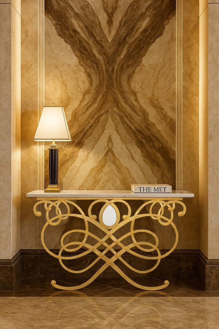 Decorative console table with intricate gold design against a marble wall.