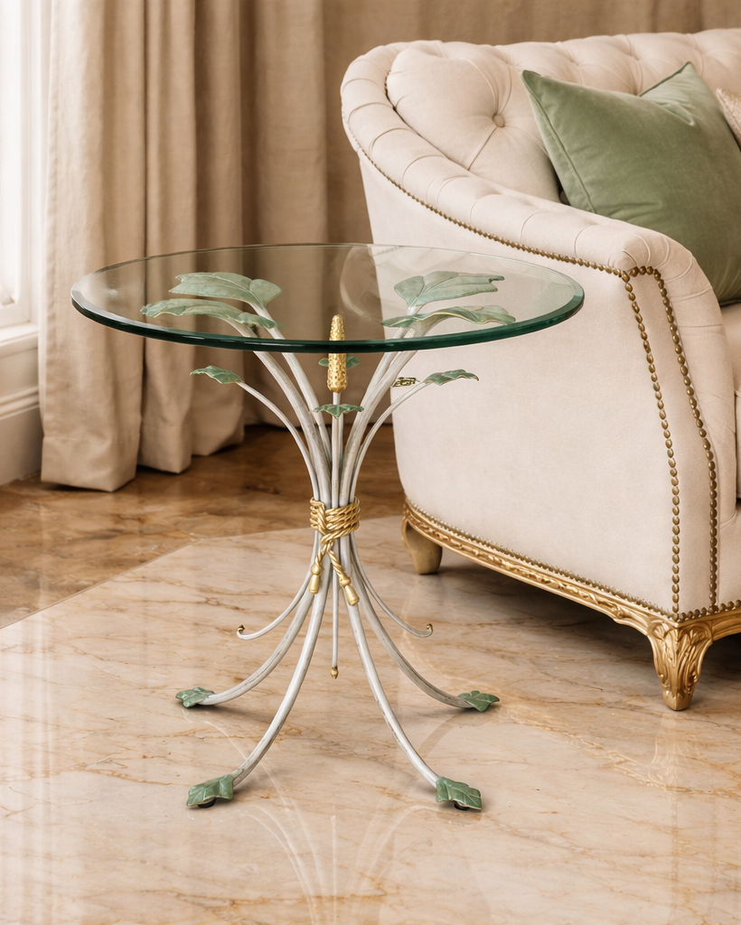 Nature inspired table with iron decorative base and glass top in front of a beige sofa with green pillows.