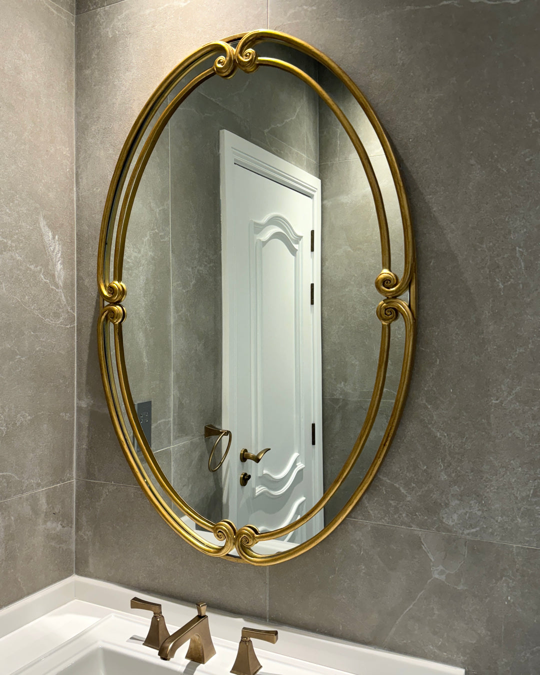 Full view of the Audrey Mirror with a gold scrollwork frame mounted on a bathroom wall