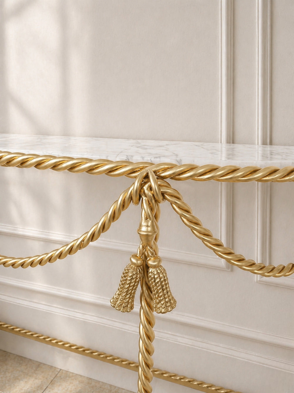 Console close up of gold decorative rope with tassel against a beige wall.