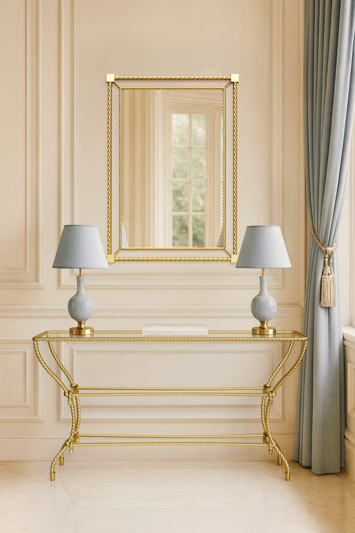 Noura console table in gold finish, featuring rope-inspired metalwork and paired with a matching mirror in a classical interior setting.