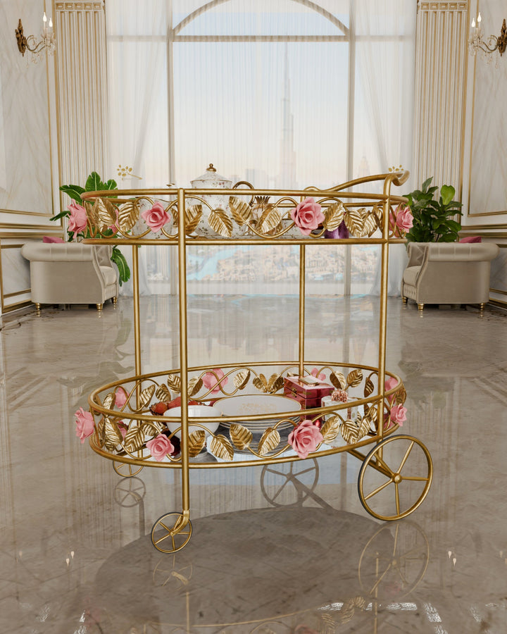 Gold Juliet serving trolley with glass shelves and pink rose metalwork, styled with tea service in an elegant living room