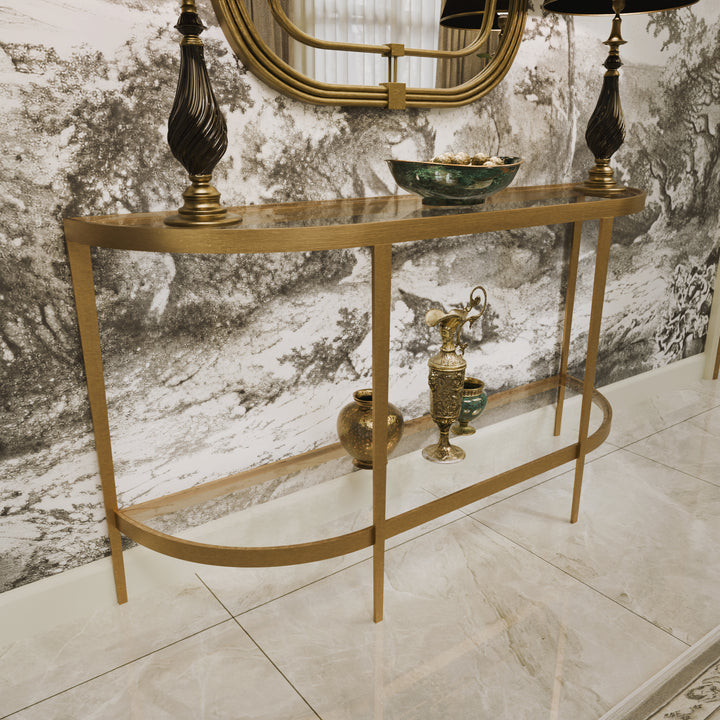 Elegant gold console styled with dark lamps, ceramics, and a scenic mural backdrop