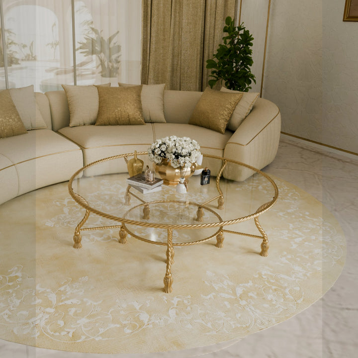 Side view of gold double-tiered coffee table with glass top and tassel feet in a refined majlis