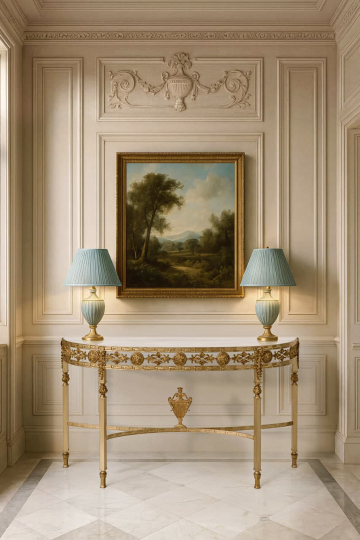 Sylvia console table in antique gold forged iron with marble top, styled in a classical interior beneath framed artwork.