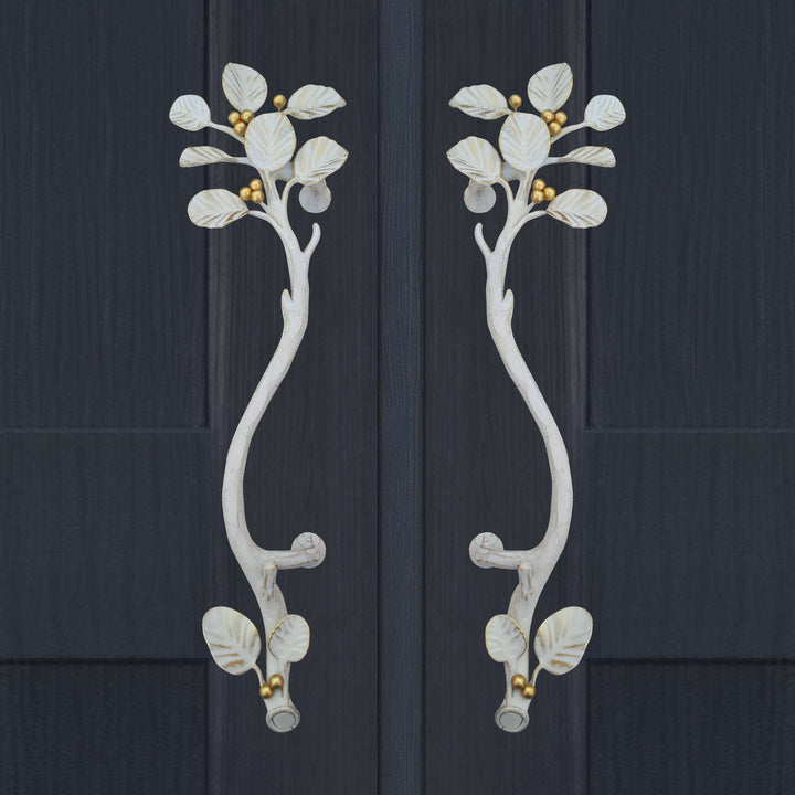 A pair of white and gold luxurious pull handles inspired by nature's leaves mounted on a closed wooden blue door