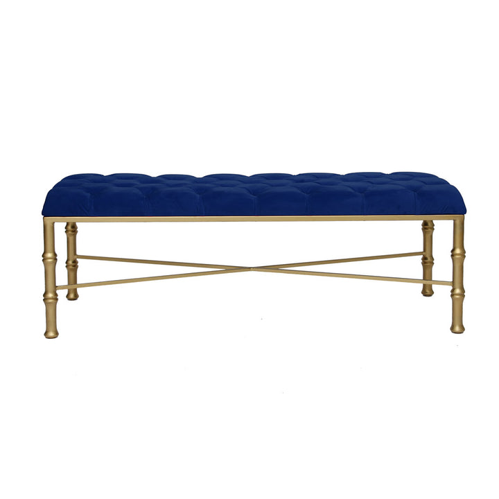 A contemporary metal golden bench with bamboo styled legs, topped with a navy blue tufted cushion