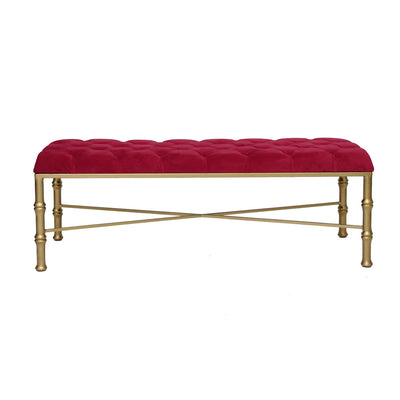 A contemporary metal golden bench with bamboo styled legs, topped with a red velvet tufted cushion