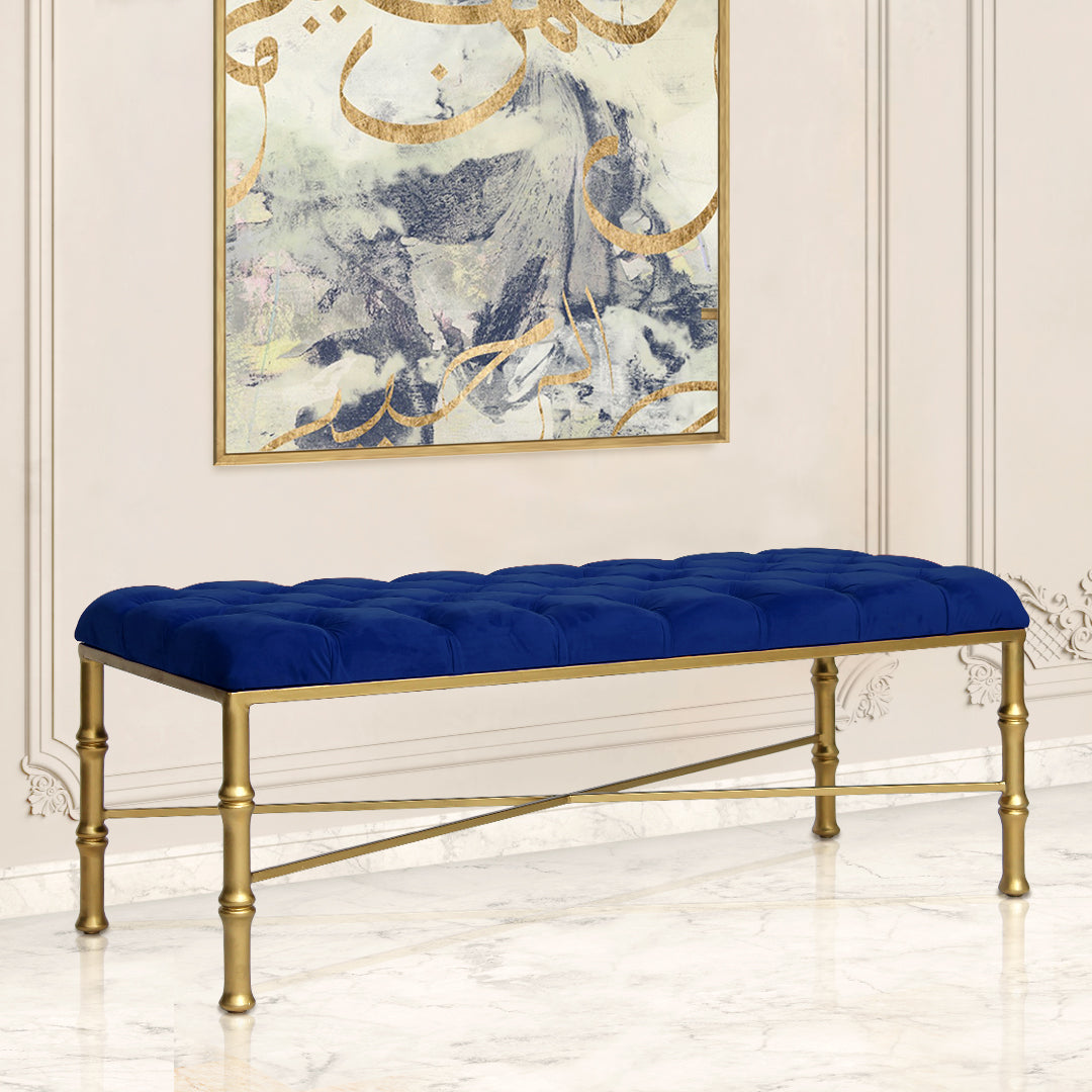A contemporary metal golden bench topped with navy blue velvet tufted upholstery in a luxurious living space