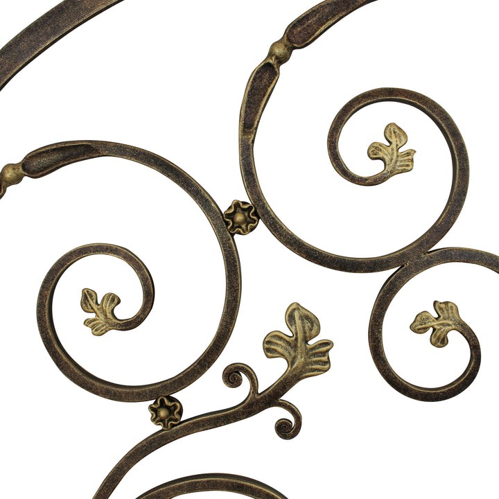 Close up of a luxurious wrought iron headboard made up of scrolls and leaves, painted in an antique bronze finish