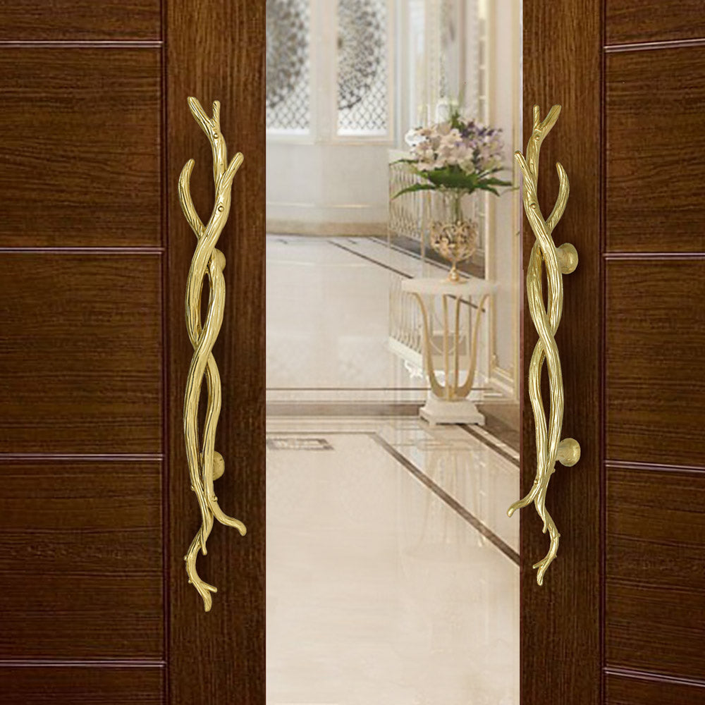 A pair of golden accent pull handles inspired by twisted branches mounted on an opened wooden door