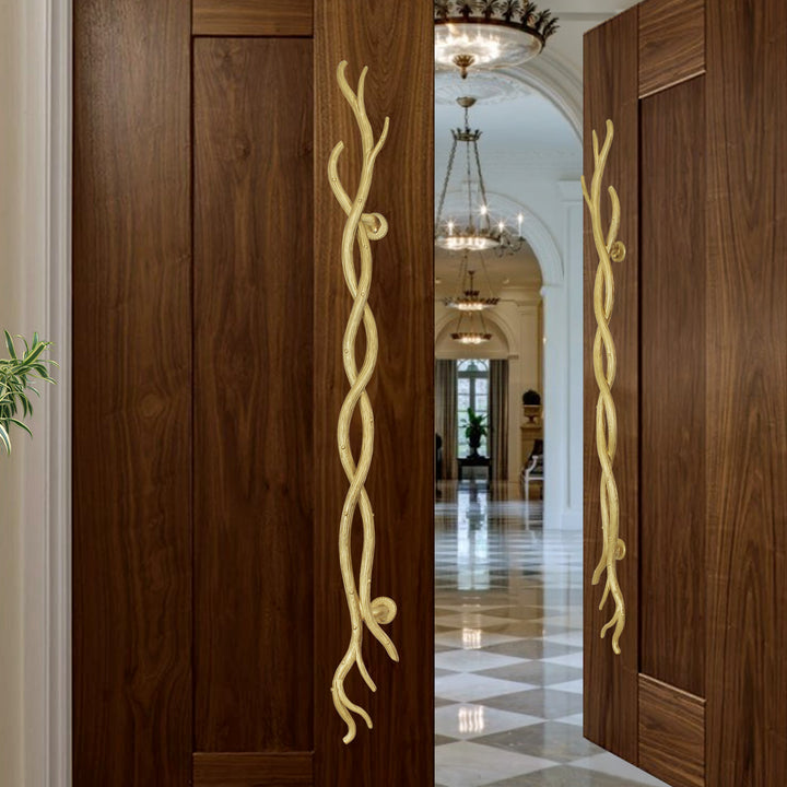 A pair of golden decorative pull handles inspired by twisted branches mounted on an opened wooden door