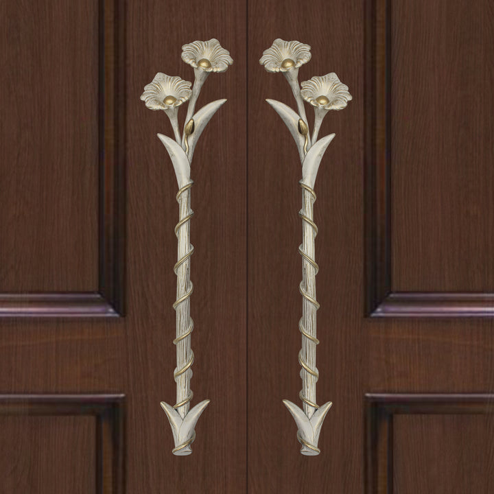 A pair of antique white decorative accent pull handles inspired by flowers mounted on a closed wooden door