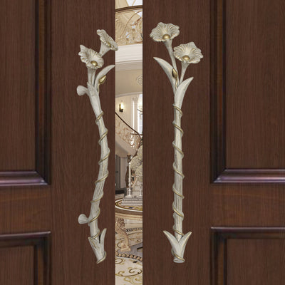 A pair of antique white decorative accent pull handles inspired by flowers mounted on an opened wooden door