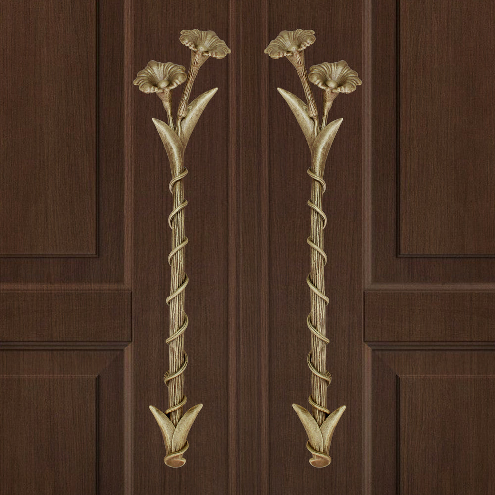 A pair of light bronze decorative accent pull handles inspired by flowers mounted on a closed wooden door