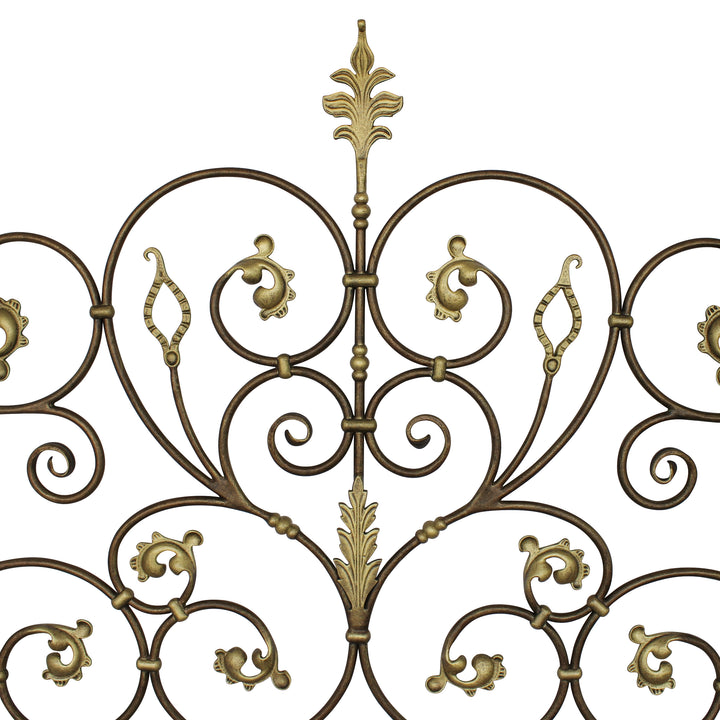 Close up of a classic metal headboard made up of scrolls and leaves, painted in an antique bronze finish