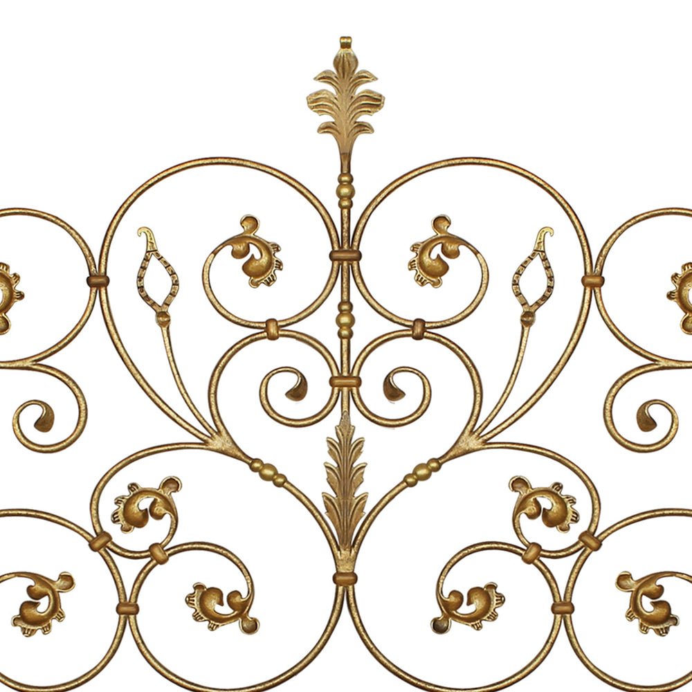 Close up of a classic metal headboard made up of scrolls and leaves, painted in an antique golden finish