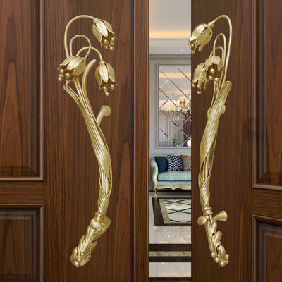 A pair of golden decorative pull handles inspired by the snowdrop flower mounted on an open wooden door