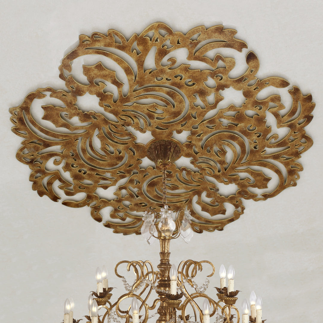 Decorative metal ceiling medallion with a lace pattern and a chandelier hanging from the center; painted in an antique golden finish