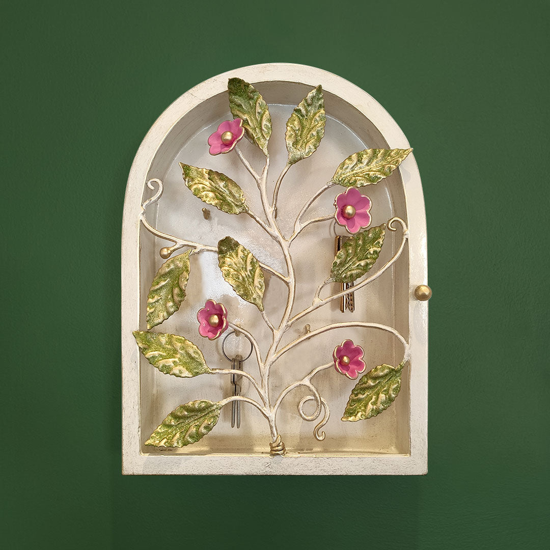 Frontal view of arched key cabinet with pink flowers and green leaves mounted on a wall