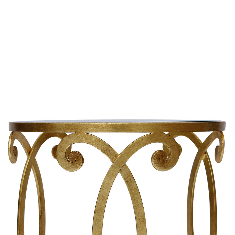 Detailed shot showing the scrolls  of a wrought iron side table with gold leaf finish