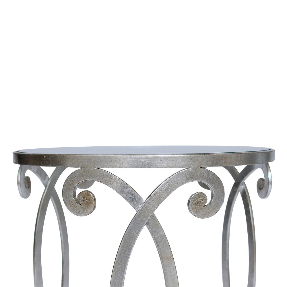 Detailed shot showing the scrolls  of a wrought iron side table with silver leaf finish