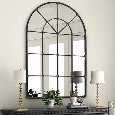 Decorative arched mirror hangs on a wall above a console table