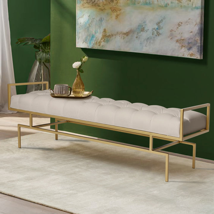 A contemporary metal golden bench topped with white leather tufted upholstery