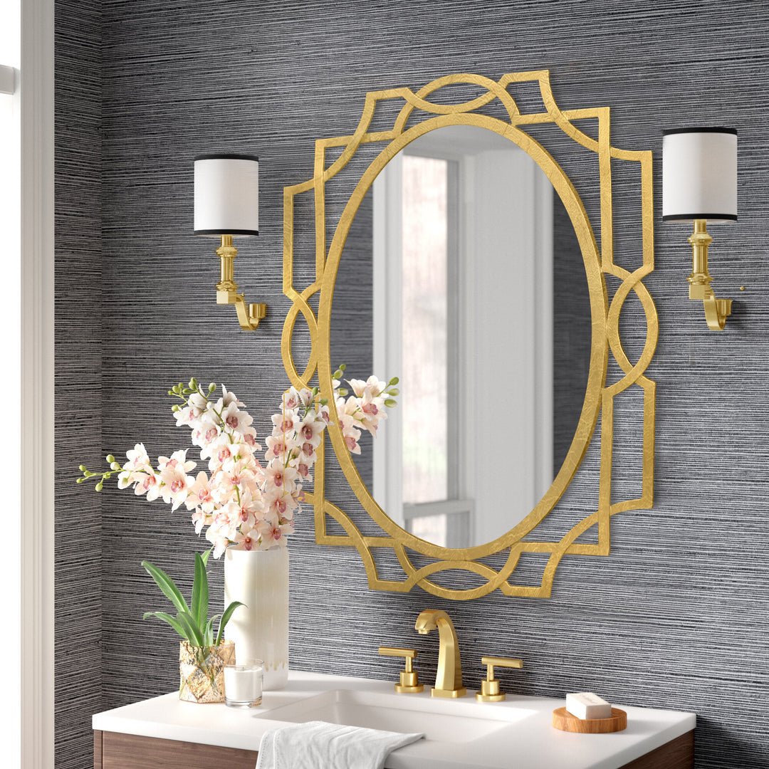 A unique oval shaped mirror with an Art Deco style and gold leaf finish sits above a wash basin