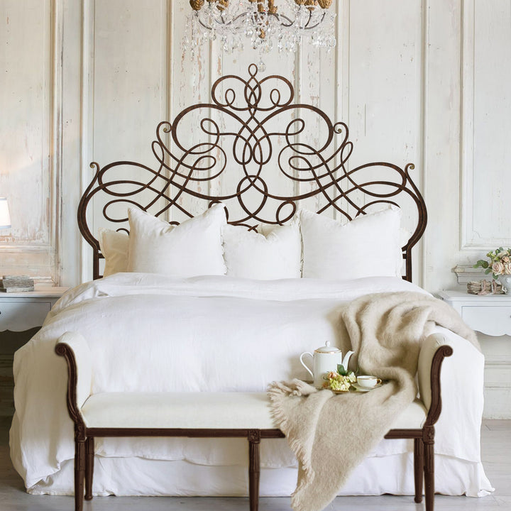 A whimsical wrought iron double bed with an organic style painted in an antique bronze finish, in a luxurious bedroom