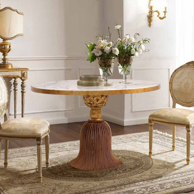 A luxurious golden round lobby table made of a metal base in the shape of a curtain tassel, topped with white marble