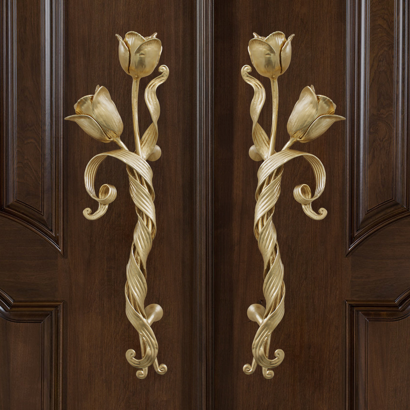 Pair of golden decorative pull handles inspired by tulips mounted on a closed wooden door