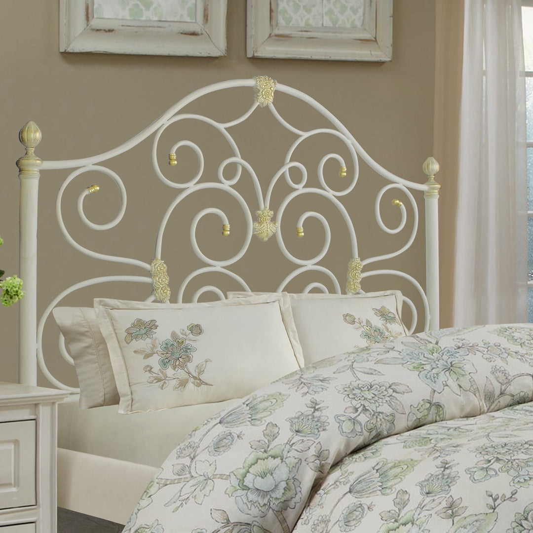 A classical wrought iron single bed with scrolls and motifs, painted in white and hints of gold