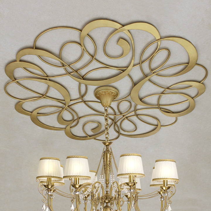 Decorative metal ceiling medallion with an organic pattern and a chandelier hanging from the center; painted in a golden finish