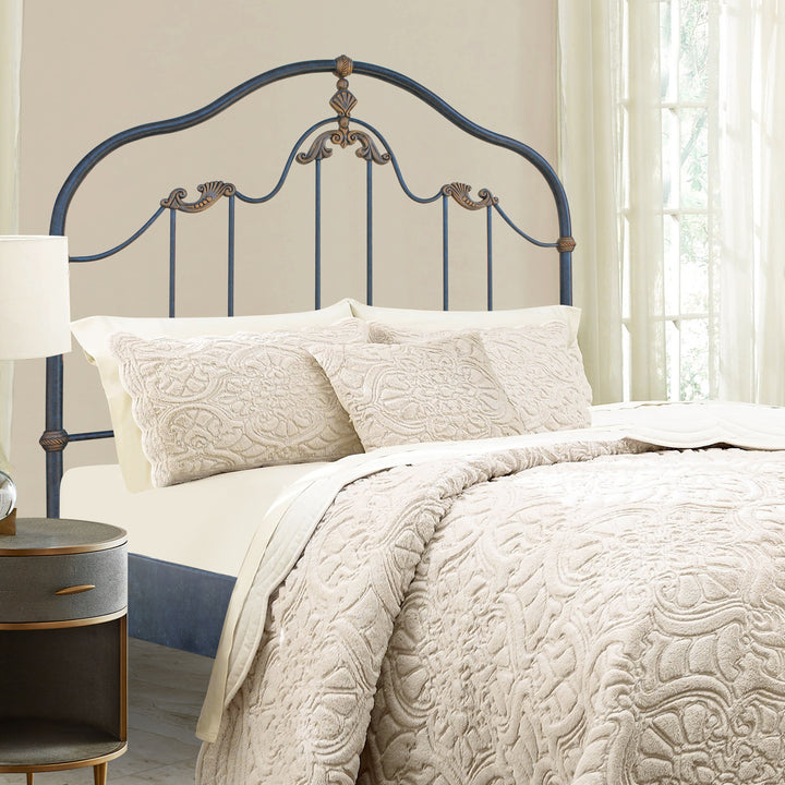 A classical wrought iron single bed with shell motifs painted in an antique blue and gold color; with beige beddings