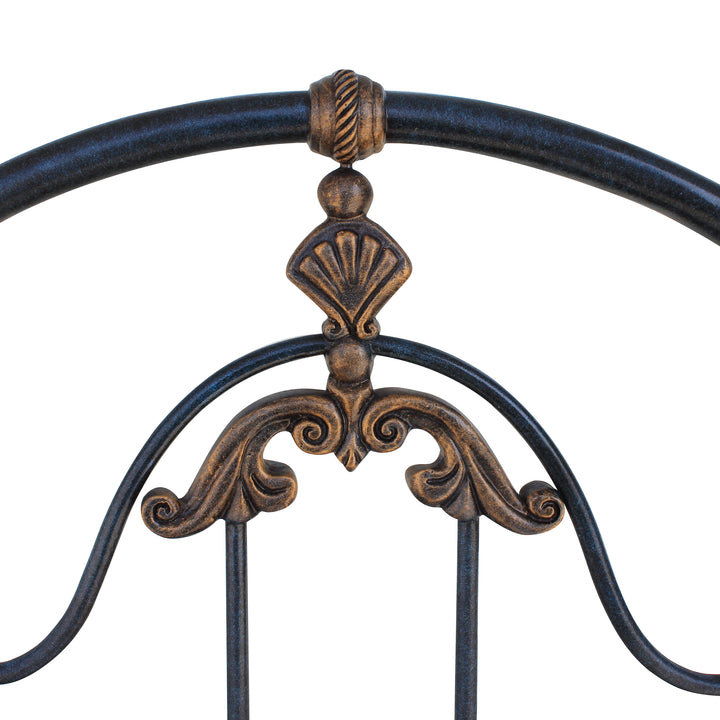 Close up of a classical wrought iron headboard with shell motifs painted in an antique deep blue and gold finish