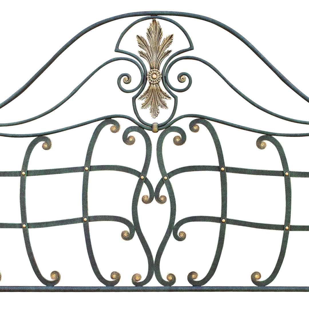 Close up of a classical wrought iron headboard with handmade scrolls painted in an antique green and golden finish