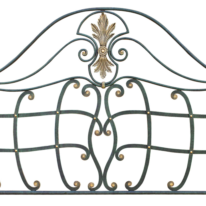 Close up of a classical wrought iron headboard with handmade scrolls painted in an antique green and golden finish